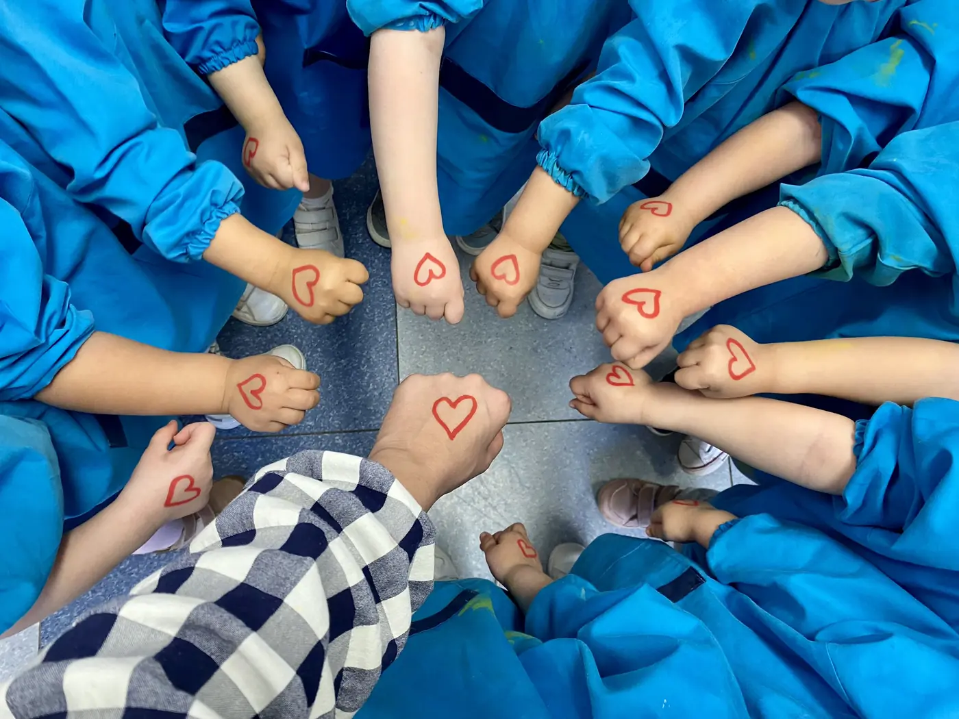 Manos de los peques de Guardería Panda con corazones formando un círculo